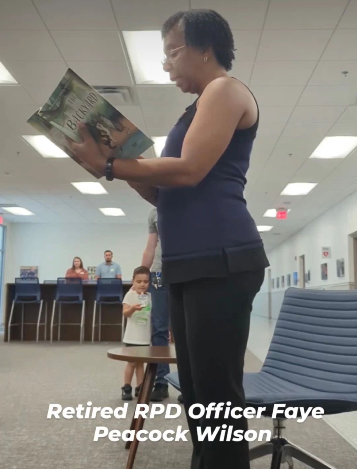 Retired Officer Faye Peacock Wilson reading The Backyard book. Retired Officer Faye Peacock Wilson reading The Backyard book.