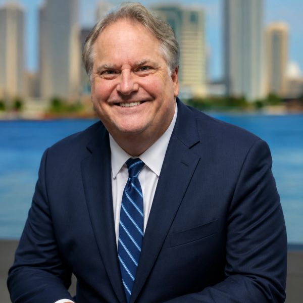 Smiling man in a suit with cityscape background.