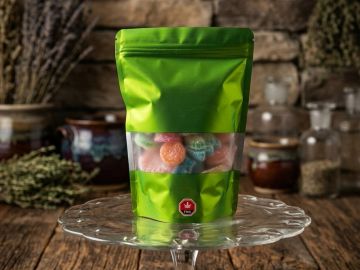 Green resealable bag with colorful candies inside on a glass stand.