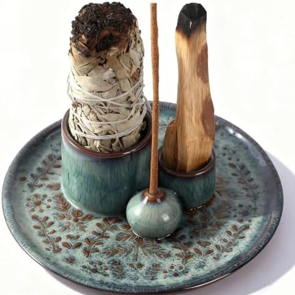 Ceramic plate holding smudge bundle, palo santo, and incense stick.
