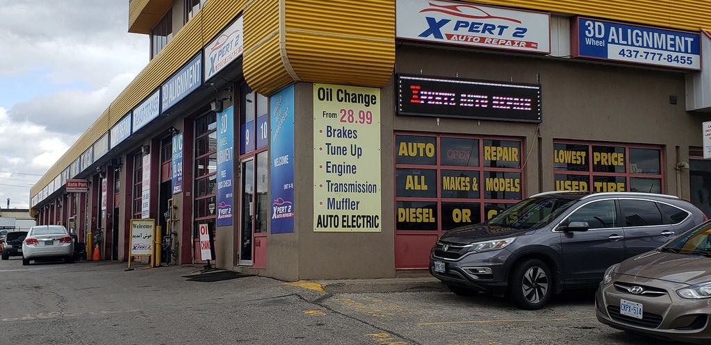 Auto repair shop with multiple service signs and parked cars.