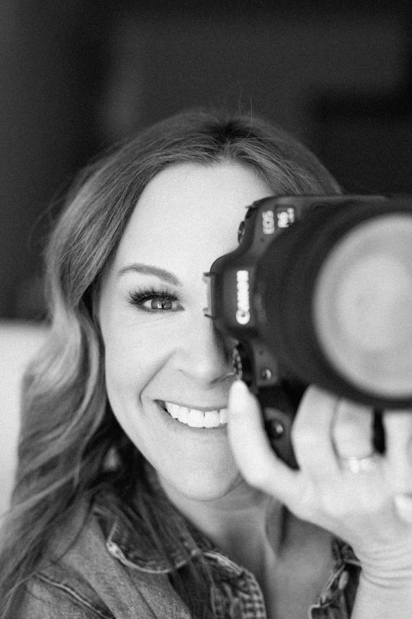 Smiling woman taking a photo with a Canon camera.