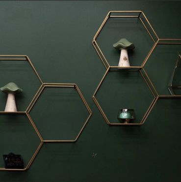 Hexagonal shelves on a dark green wall with decorative items.