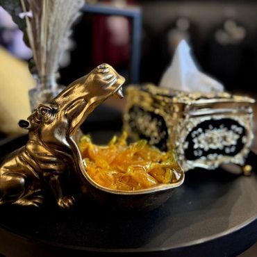 Golden hippo-shaped bowl filled with wrapped candies on a black surface.