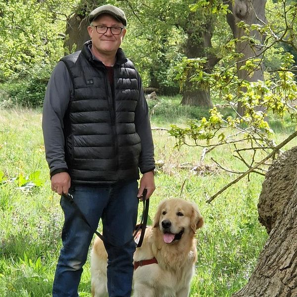 Mark on a dog walk, stood with his golden retriever dog Dudley.