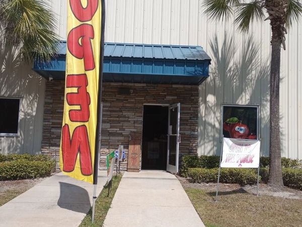 Entrance of a building with open door, 'OPEN' flag, and a promotional sign.