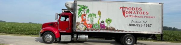 A red truck with a colorful vegetable-themed advertisement on its side.