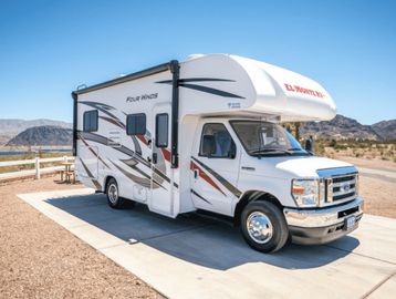 White Class C motorhome parked on a sunny desert road.