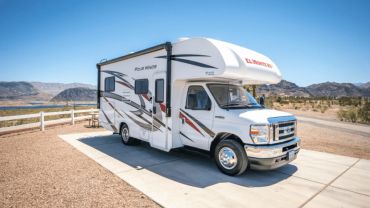 White motorhome parked on a concrete pad in a desert landscape.