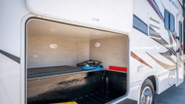 Open storage compartment of a white RV showing internal space and items.