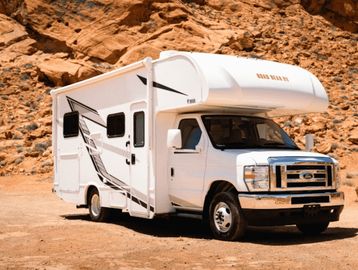 White RV parked in a rocky desert area under sunlight.