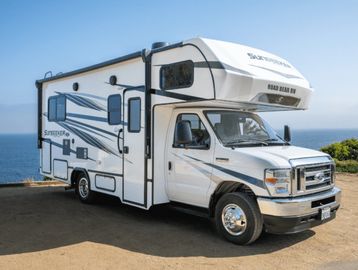 White recreational vehicle parked by the ocean on a sunny day.