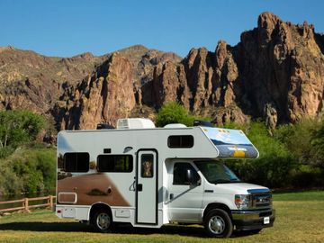 A camper van parked in a scenic mountainous area under clear blue sky.
