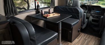 Cozy black leather seating area with dining table inside an RV.