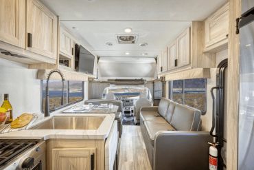 Interior of a modern RV with kitchen and seating area.