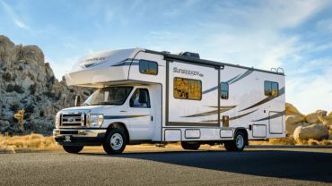 White motorhome parked outdoors near rocky terrain.
