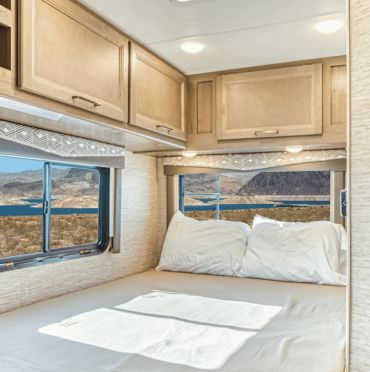 Cozy RV bedroom with large windows showcasing a scenic desert view.