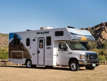 White RV parked outdoors with scenic mountains in the background.