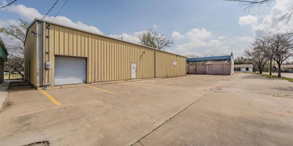 Large beige industrial building with parking space.