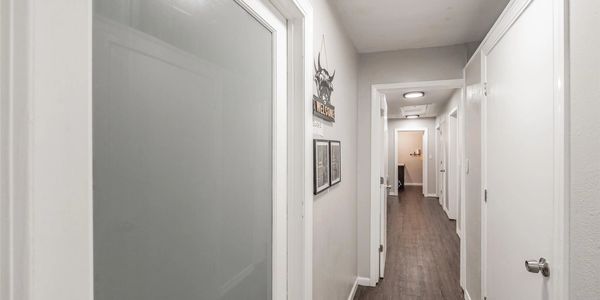 Long hallway with white doors and wood flooring.