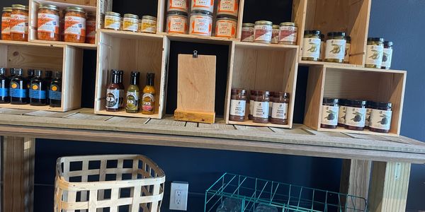 Wooden shelves displaying jars of preserves and sauces in a rustic setting.