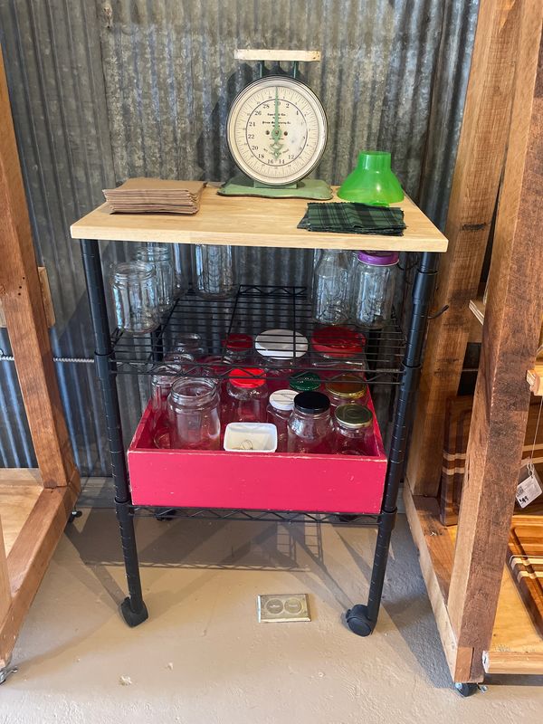 Vintage scale on a wooden top with jars and cloths on a metal cart.
