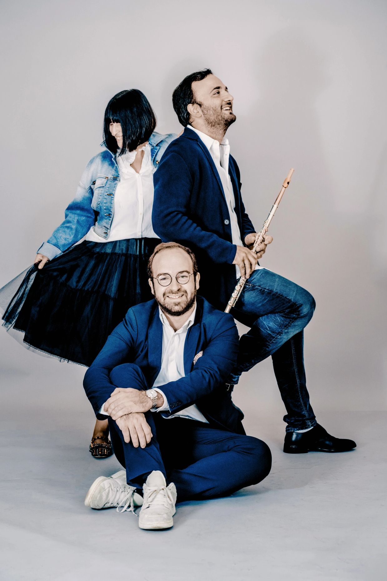 Three people posing, one holding a flute.