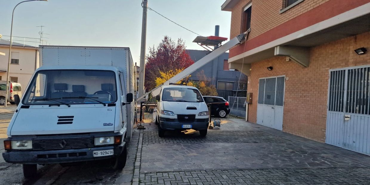 un  autoscala per traslochi a fianco a un furgone agganciata a una finestra di un edificio