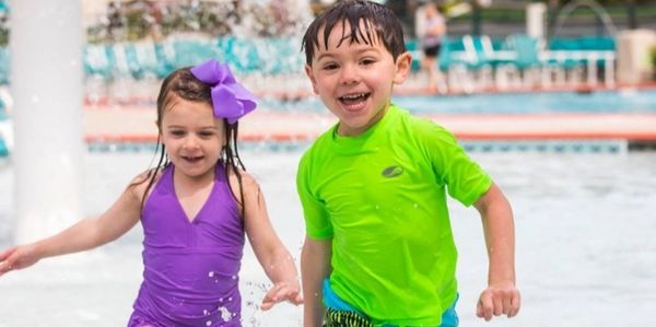 Two kids holding each other and playing in the pool