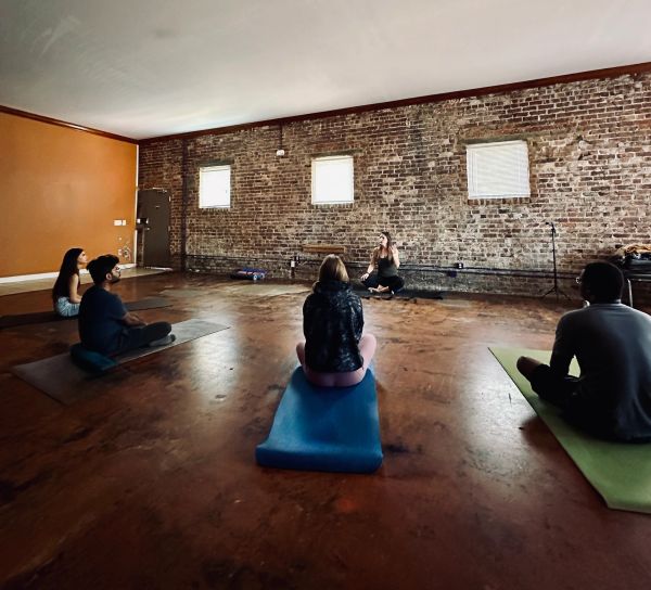 People in a yoga or meditation class in a brick-walled room.