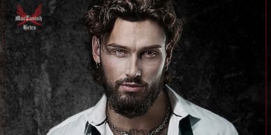 A bearded man with intense eyes and curly hair wearing a white shirt and chains.