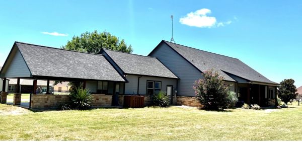 A spacious house with multiple roof sections under a bright blue sky.