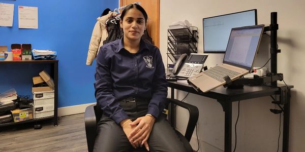 Woman sitting in an office with a laptop and phone on the desk.