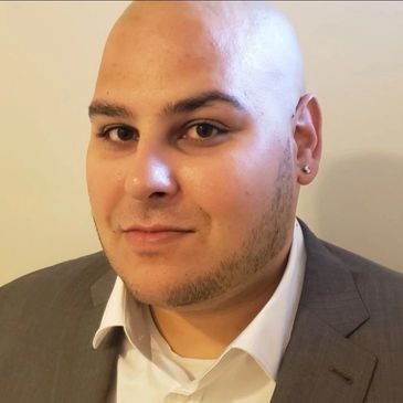 A smiling bald man in a grey suit and white shirt.