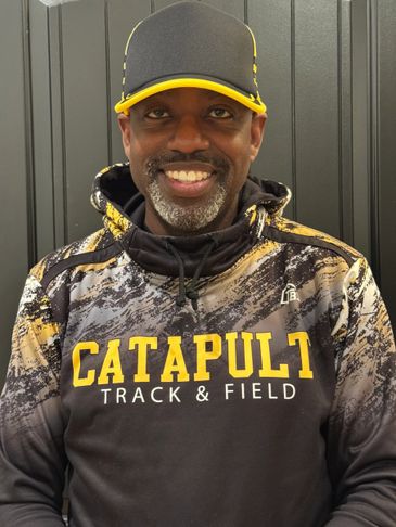 Smiling man in black and yellow Catapult Track &amp; Field hoodie and cap.