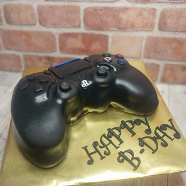 Cake shaped like a PlayStation controller with birthday message.