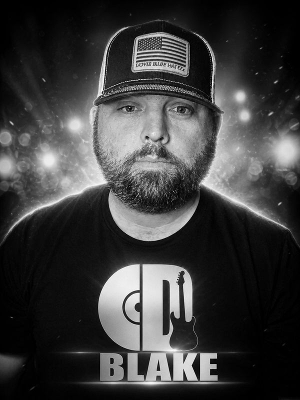 Black and white portrait of a man wearing a cap and a "Blake" t-shirt.