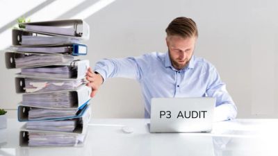 Man working on a P3 audit with large stack of files.
