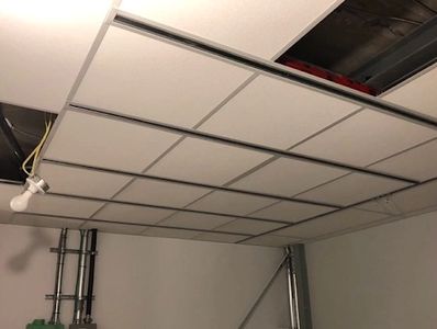 Dropped ceiling with some panels missing and exposed pipes.
