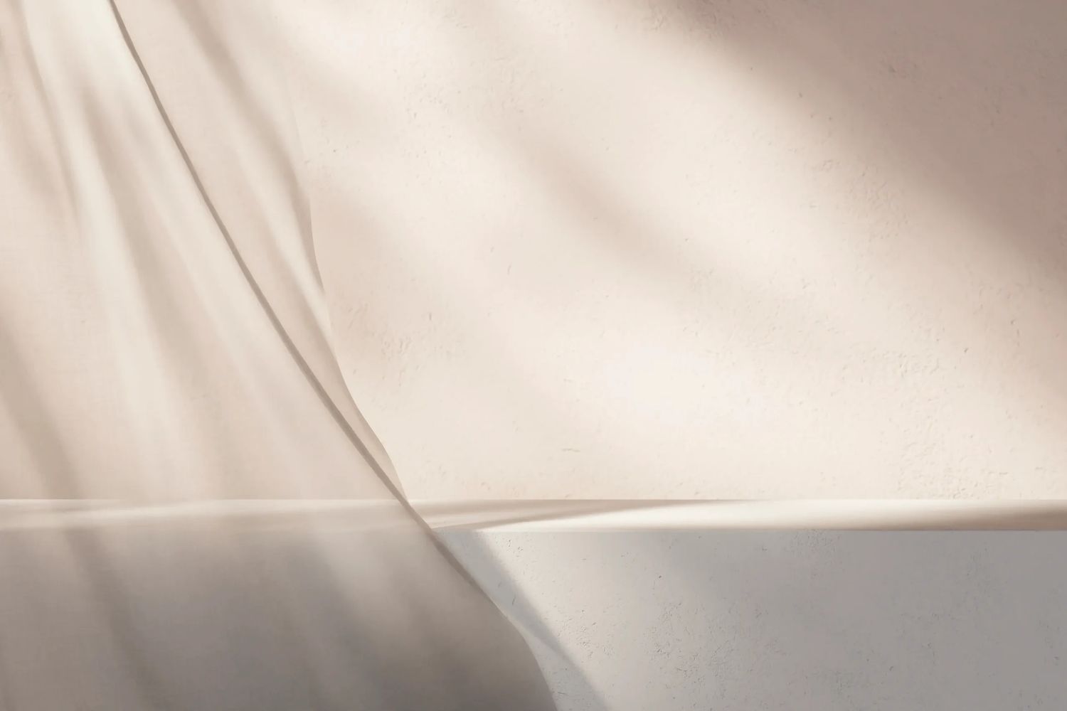 Soft beige curtain and wall with shadows creating a peaceful atmosphere.