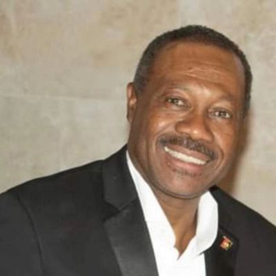 Smiling man in a black suit jacket with a white shirt.
