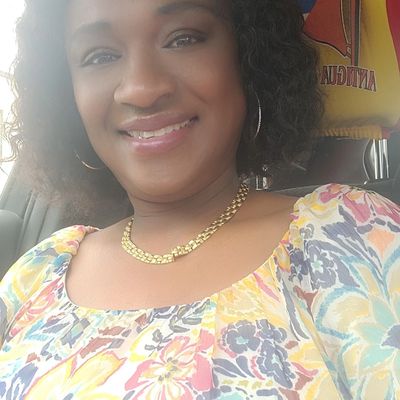 Smiling woman in colorful floral top and gold necklace.