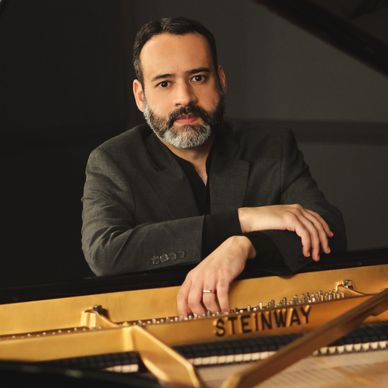 Man with beard posing at a Steinway piano.