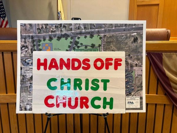 Sign reads 'HANDS OFF CHRIST CHURCH' in bold red and green letters.