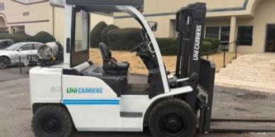White UniCarriers forklift parked outdoors near a building.