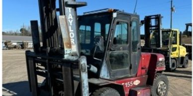 Red Taylor forklift parked on a dirt lot under a clear blue sky.