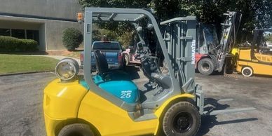 Yellow Komatsu forklift parked outdoors with visible controls and tires.