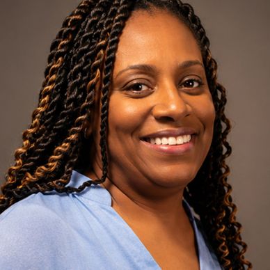 Smiling woman with braided hair wearing a light blue top.