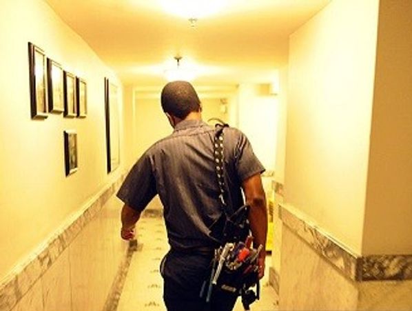 A maintenance worker walking down a hallway with tools.