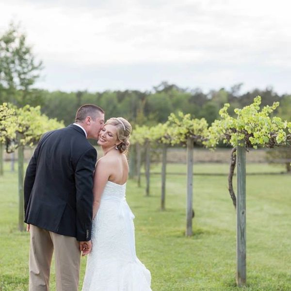 Bride and groom share a tender moment in a vineyard.